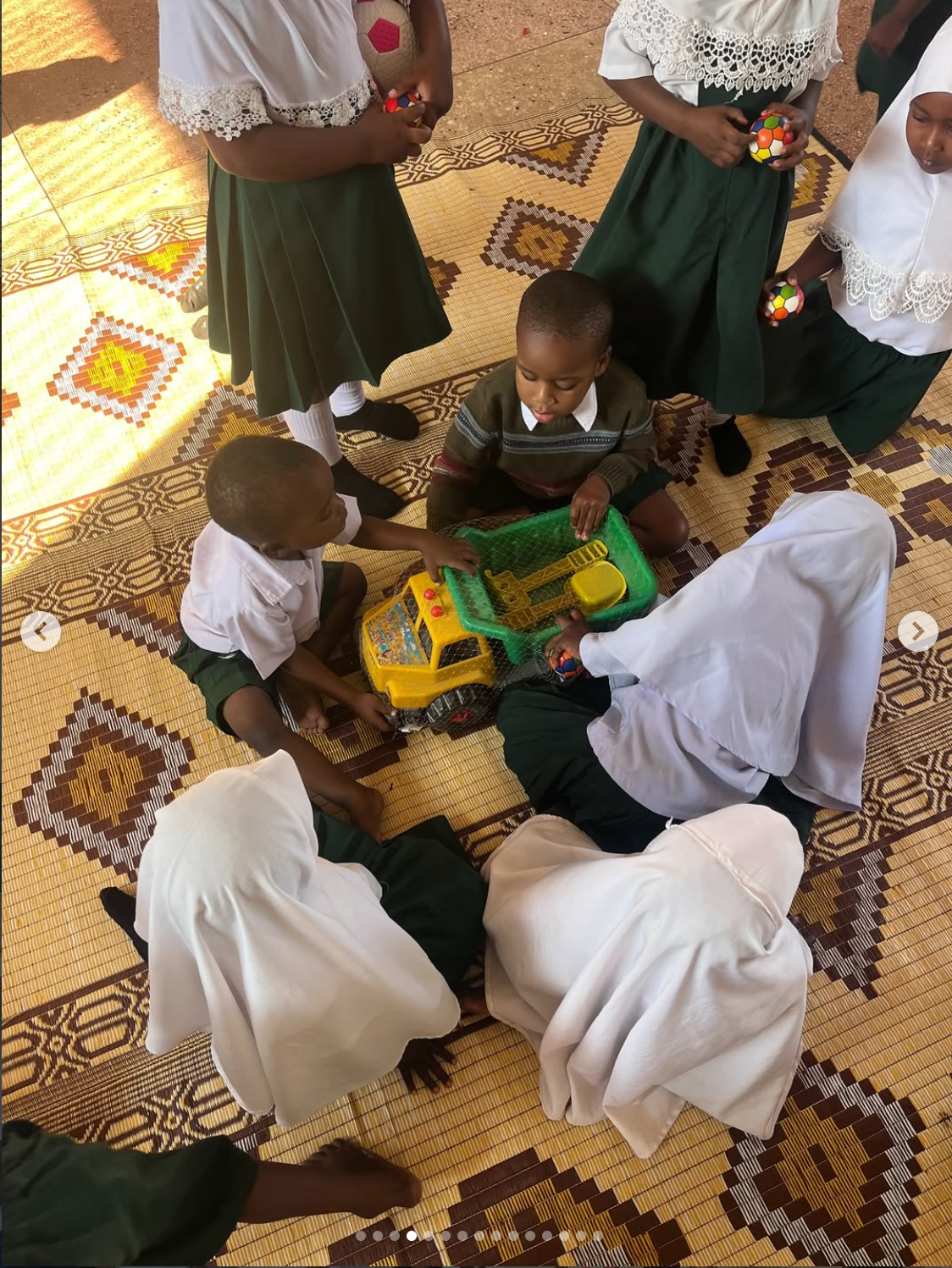 Young children playing with toys on the floor at a day care centre in Zanzibar